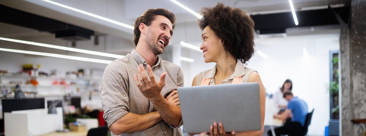 A man and woman engaged in conversation in a professional office setting.